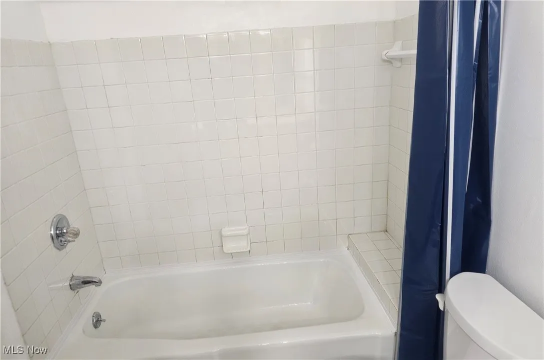 Full bathroom featuring shower / tub combo with curtain and toilet