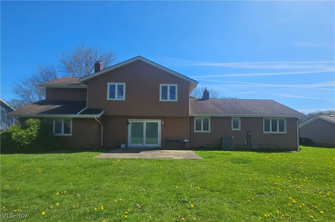 Back of house featuring a patio area, central AC, a yard, and a chimney