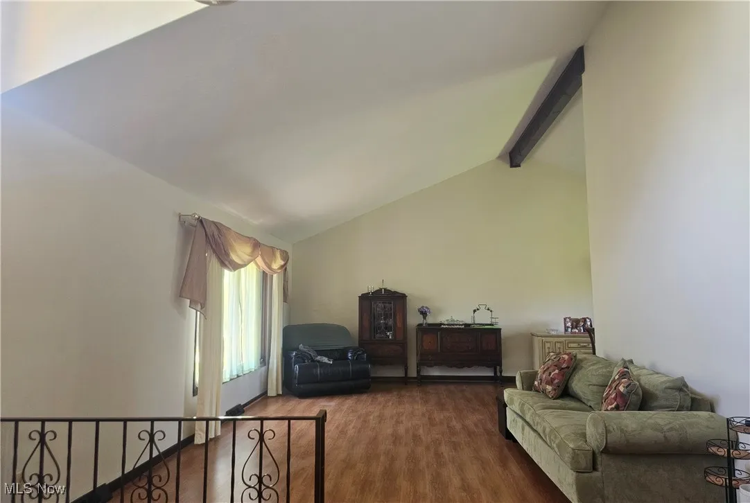 Living area with lofted ceiling with beams and wood finished floors