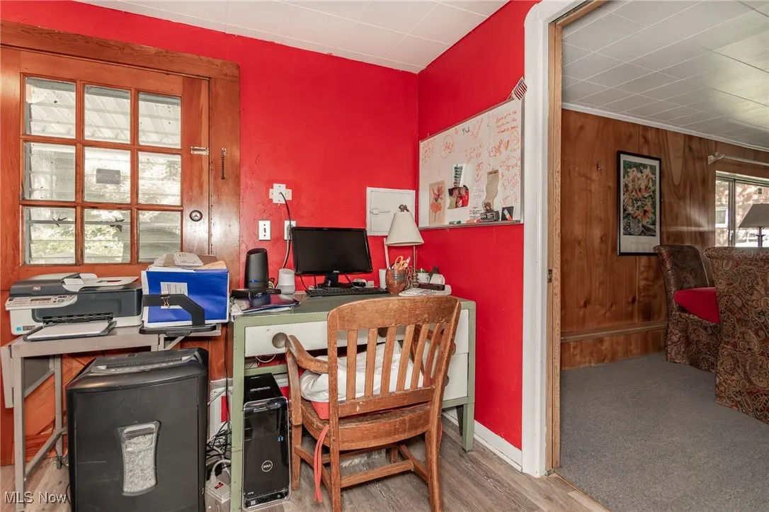 Home office with baseboards, wood finished floors, and wooden walls