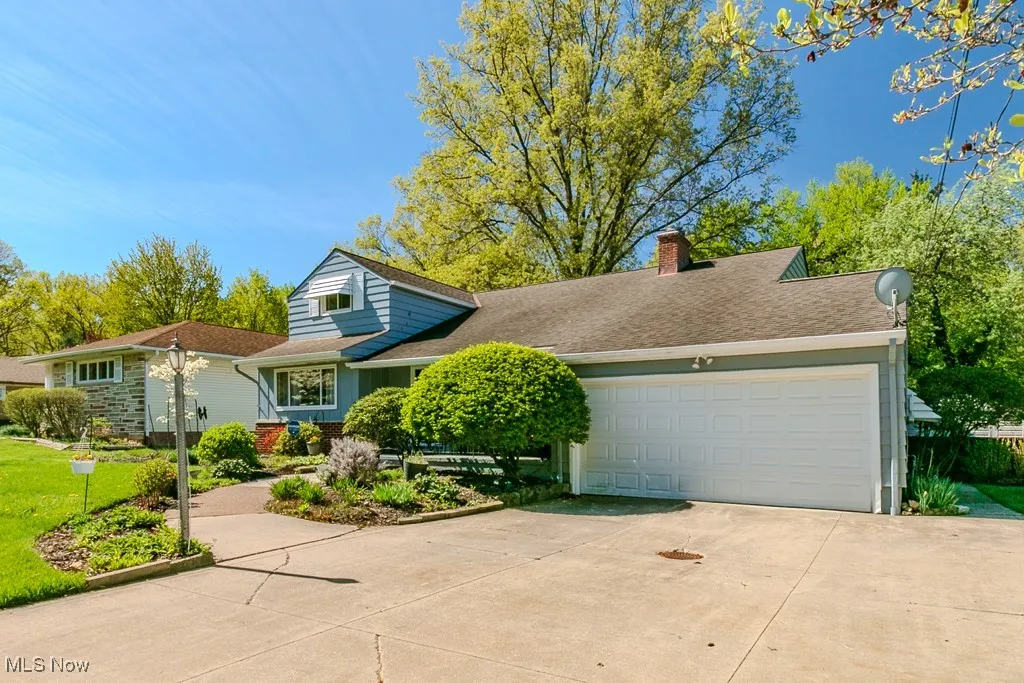 View of front of home featuring a garage, a shingled roof, a chimney, and concrete driveway