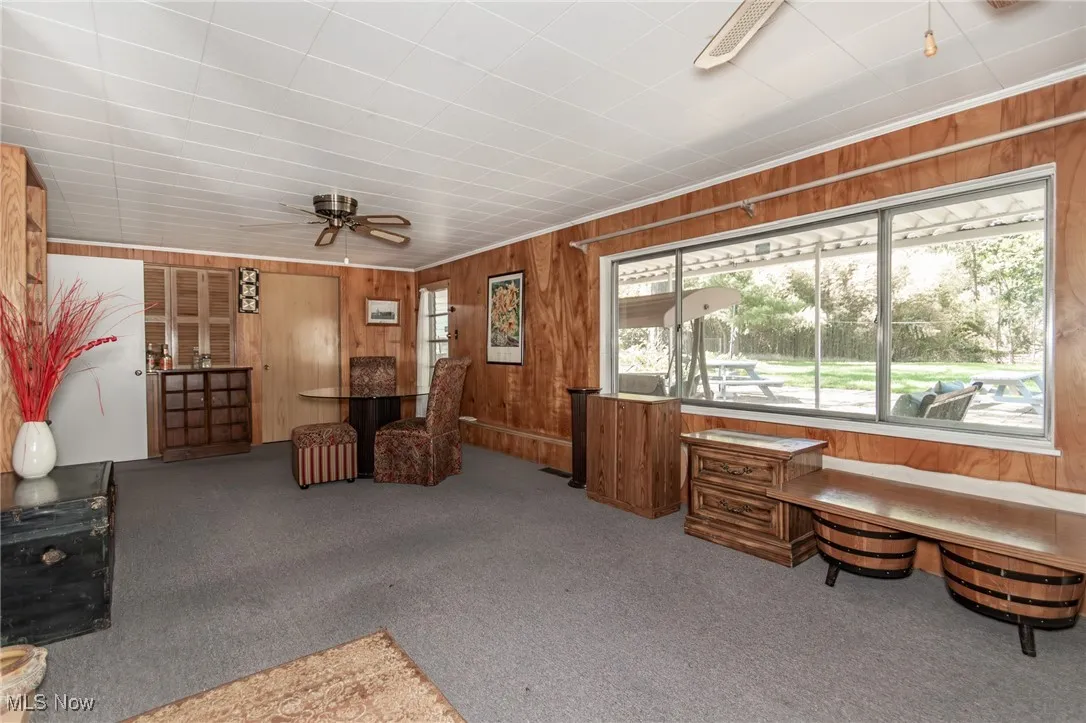 Sitting room featuring carpet flooring, a ceiling fan, and wooden walls