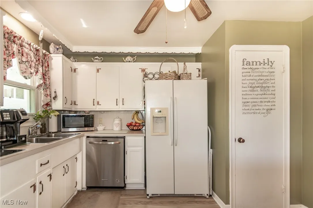 Kitchen featuring light countertops, appliances with stainless steel finishes, ceiling fan, and white cabinetry
