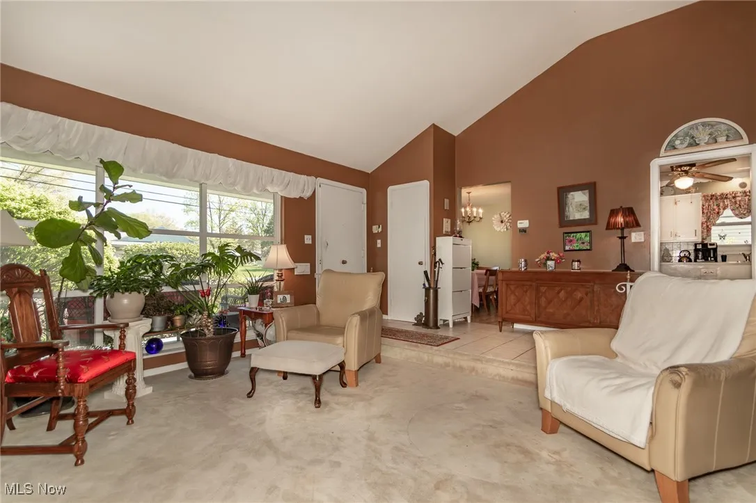Living area with high vaulted ceiling, ceiling fan, and carpet