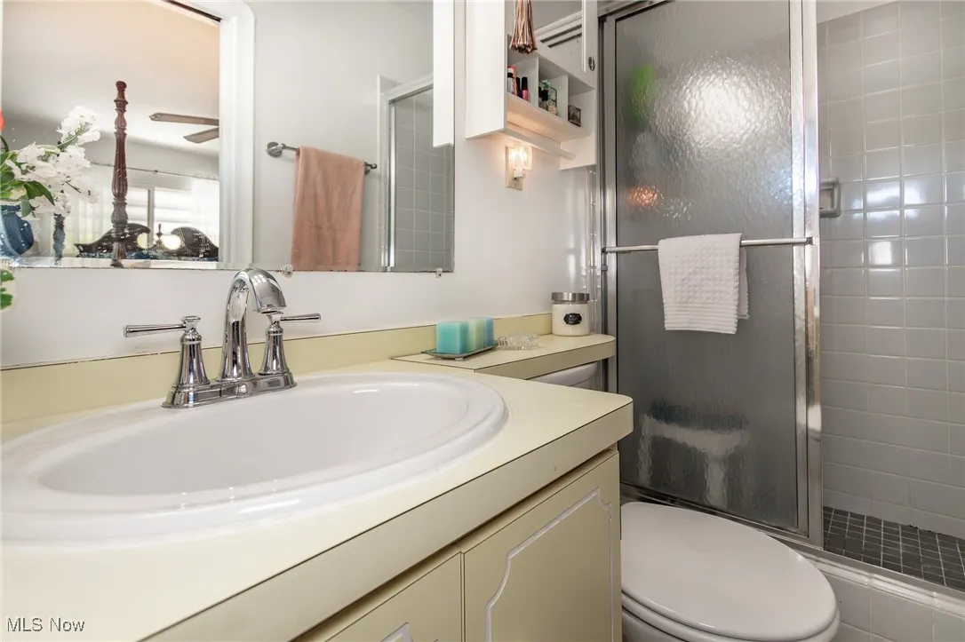 Full bath with vanity, a stall shower, and toilet