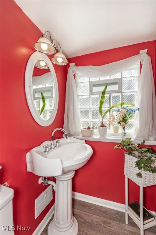 Bathroom featuring toilet, baseboards, visible vents, and wood finished floors