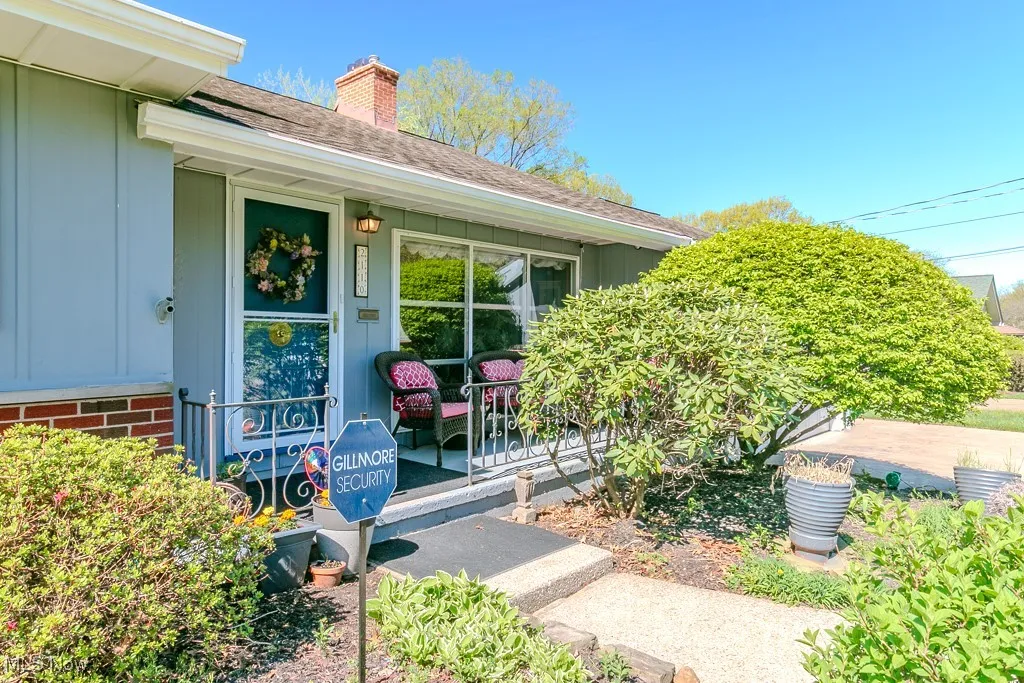 Property entrance featuring a shingled roof, a chimney, and a porch