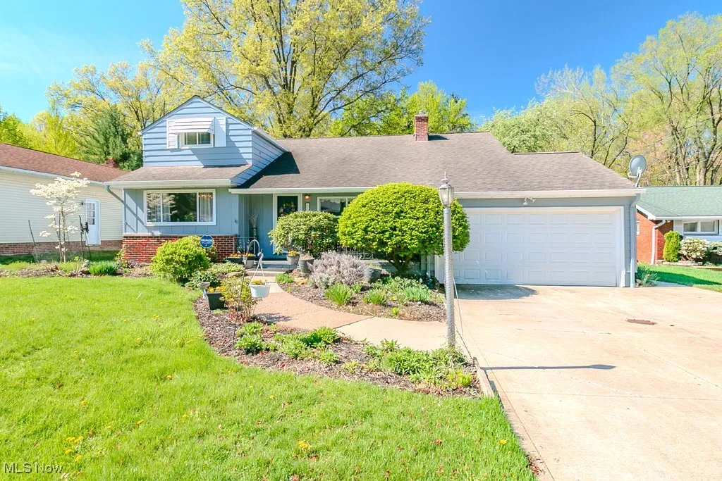 View of front of home with a garage, a front yard, a chimney, brick siding, and concrete driveway