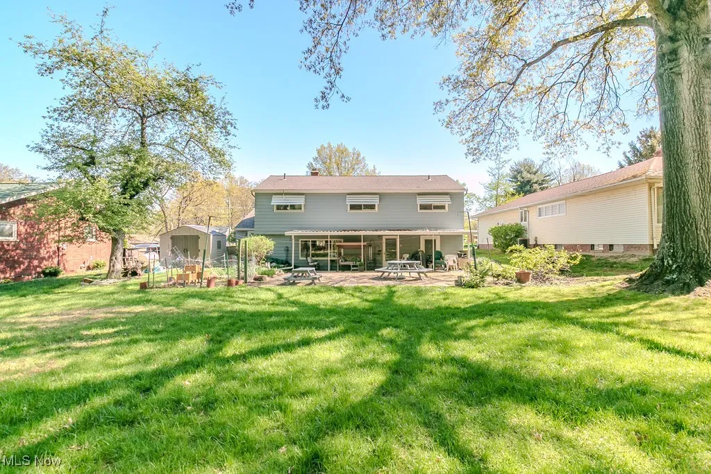 Back of house with an outbuilding, a patio, a chimney, and a yard