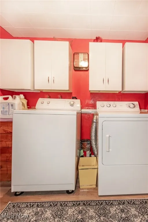 Washroom with cabinet space, independent washer and dryer, and light wood finished floors