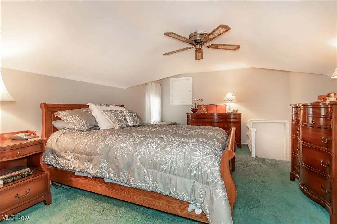 Bedroom featuring a ceiling fan, vaulted ceiling, and carpet