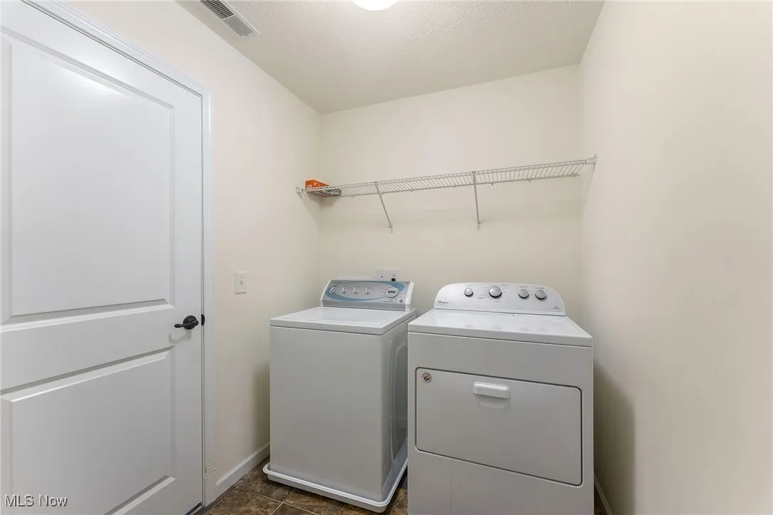 Clothes washing area with laundry area, visible vents, washing machine and dryer, and baseboards