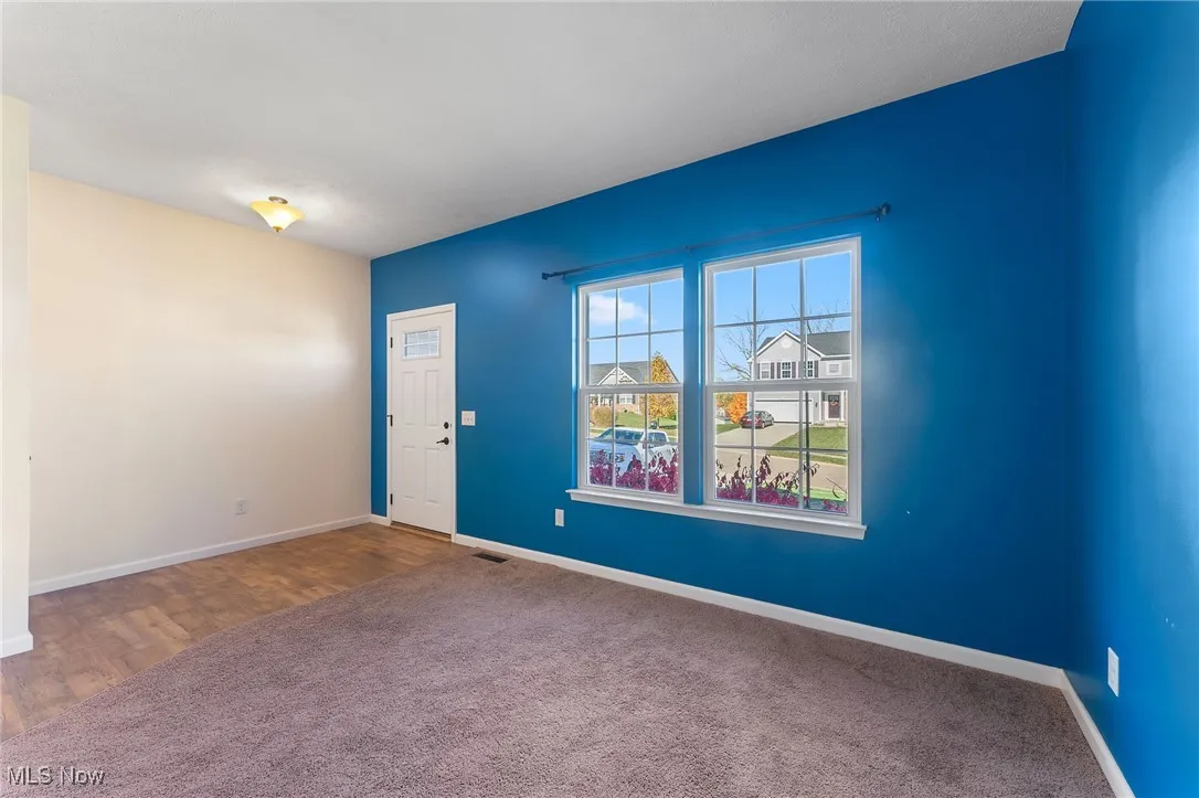 Unfurnished room with baseboards, carpet flooring, wood finished floors, and visible vents