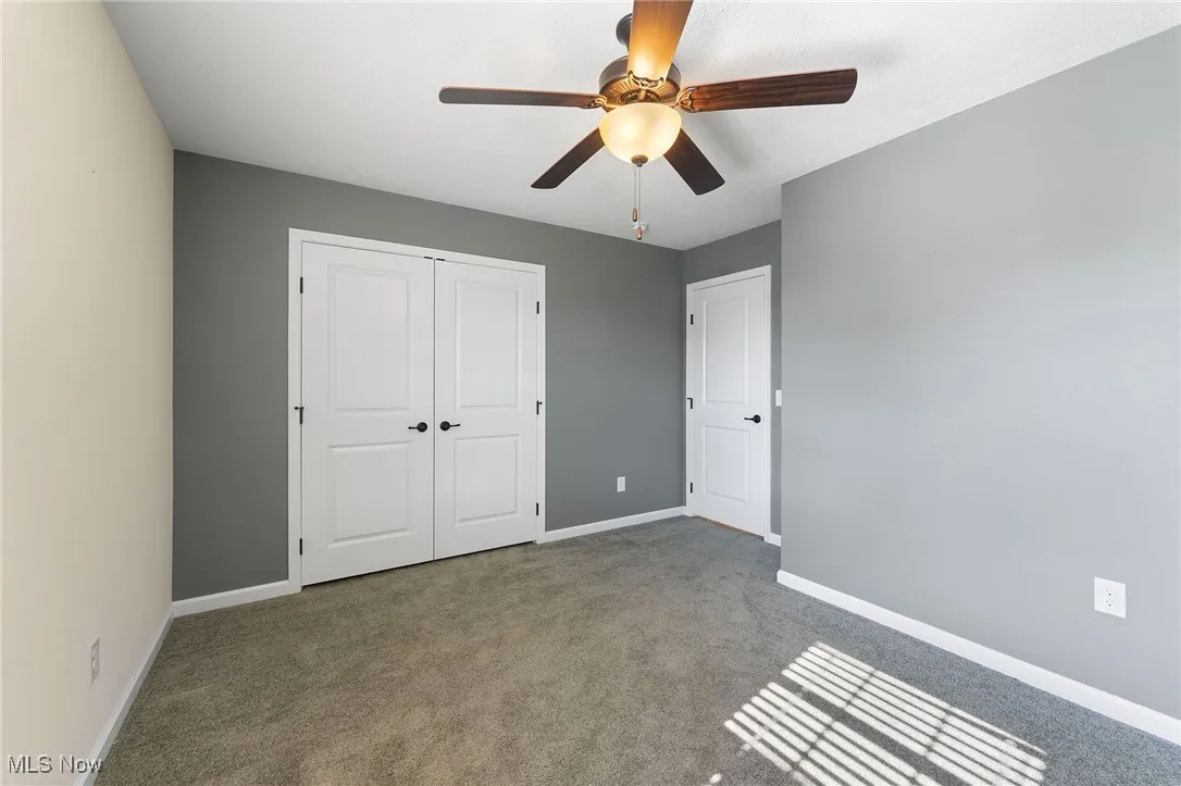 Unfurnished bedroom featuring carpet flooring, baseboards, ceiling fan, and a closet