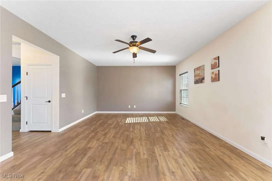 Spare room featuring stairs, ceiling fan, baseboards, and light wood finished floors