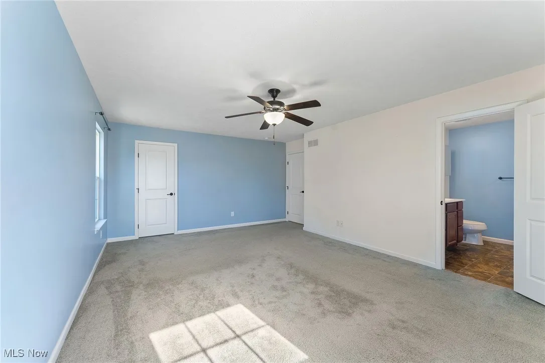 Master bedroom with connected bathroom, carpet floors, a ceiling fan, baseboards, and visible vents