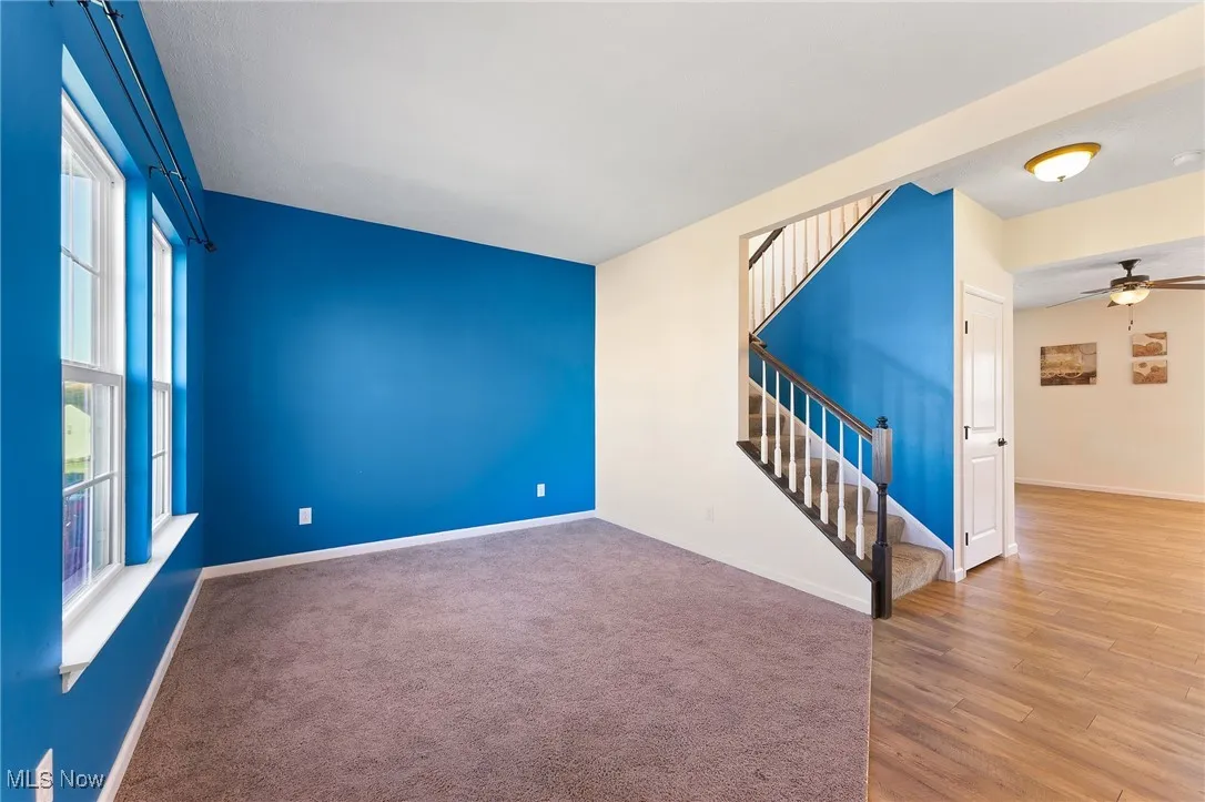 Spare room featuring stairway, baseboards, a ceiling fan, and wood finished floors