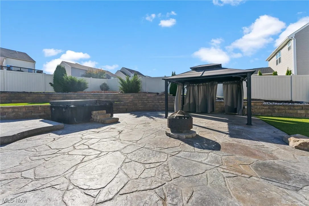 View of patio featuring a fenced backyard, a gazebo, a hot tub, and a fire pit