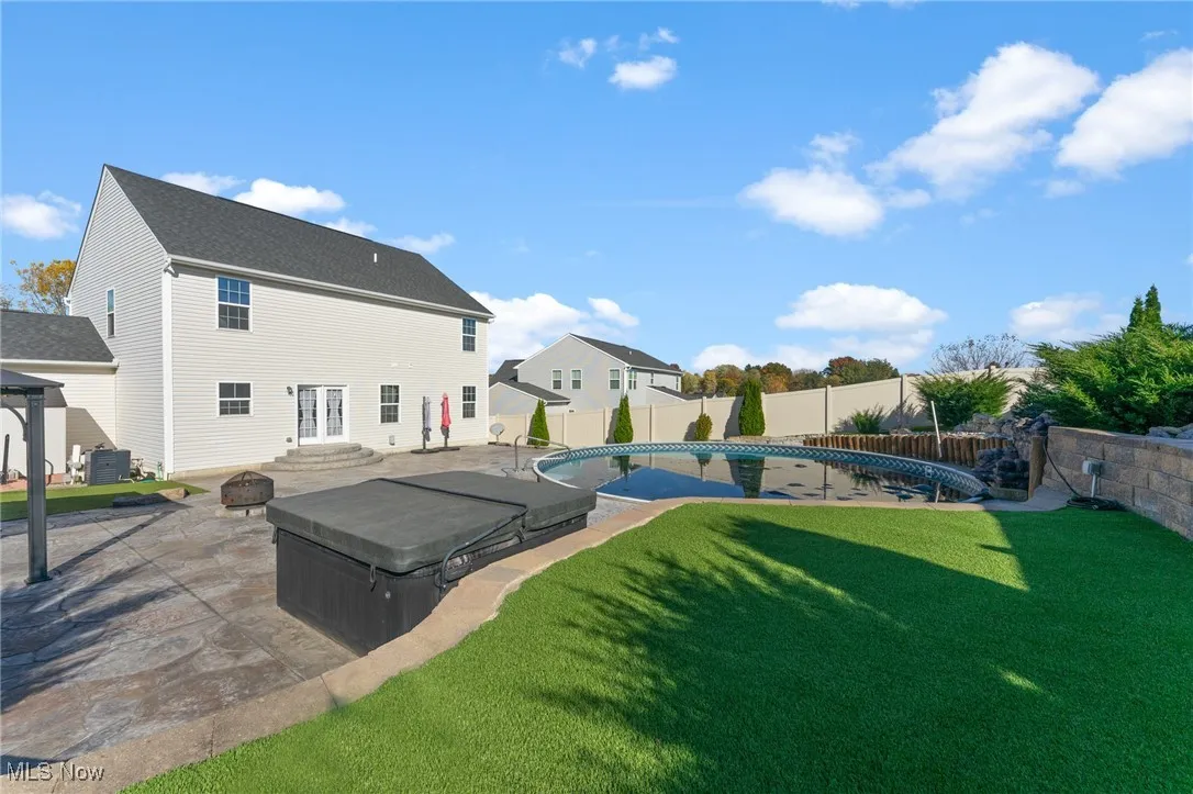 Back of property featuring a fenced in pool, a fenced backyard, cooling unit, a patio area, and a lawn