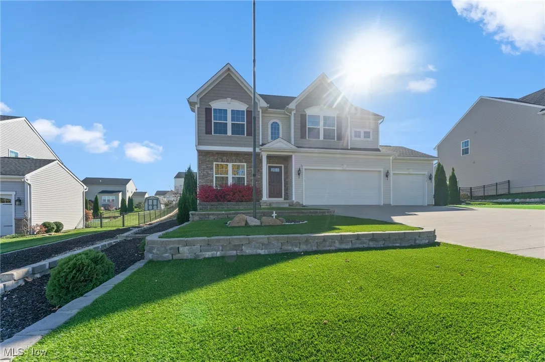 View of front of property featuring fence, stone siding, a garage, a front yard, and driveway