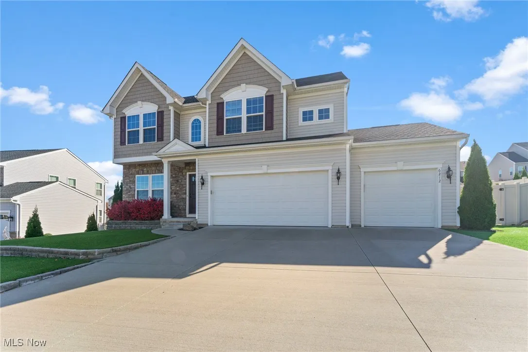 View of front of house featuring an attached garage, stone siding, and concrete driveway