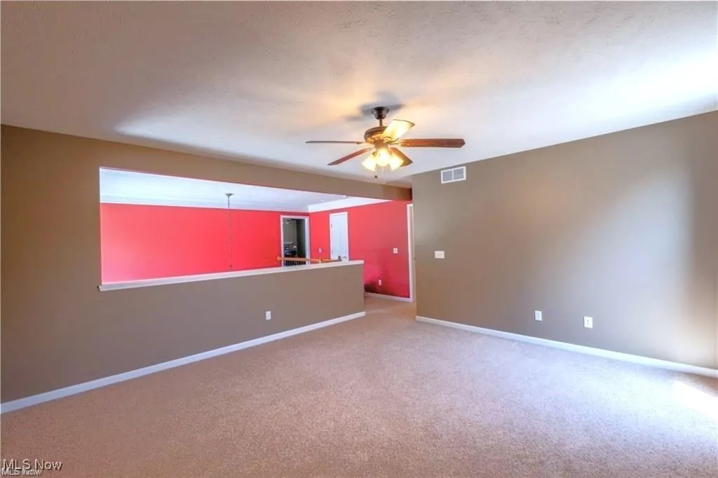 Spare room with baseboards, ceiling fan, carpet, and visible vents