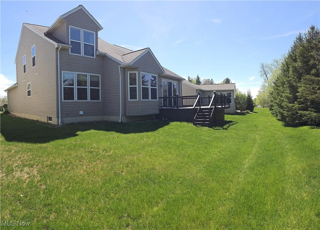 Back of property with a wooden deck and a yard