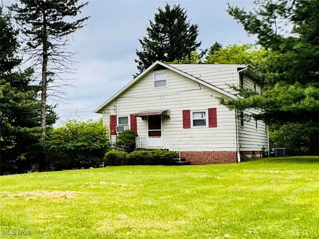 View of front of home with a front lawn and central AC