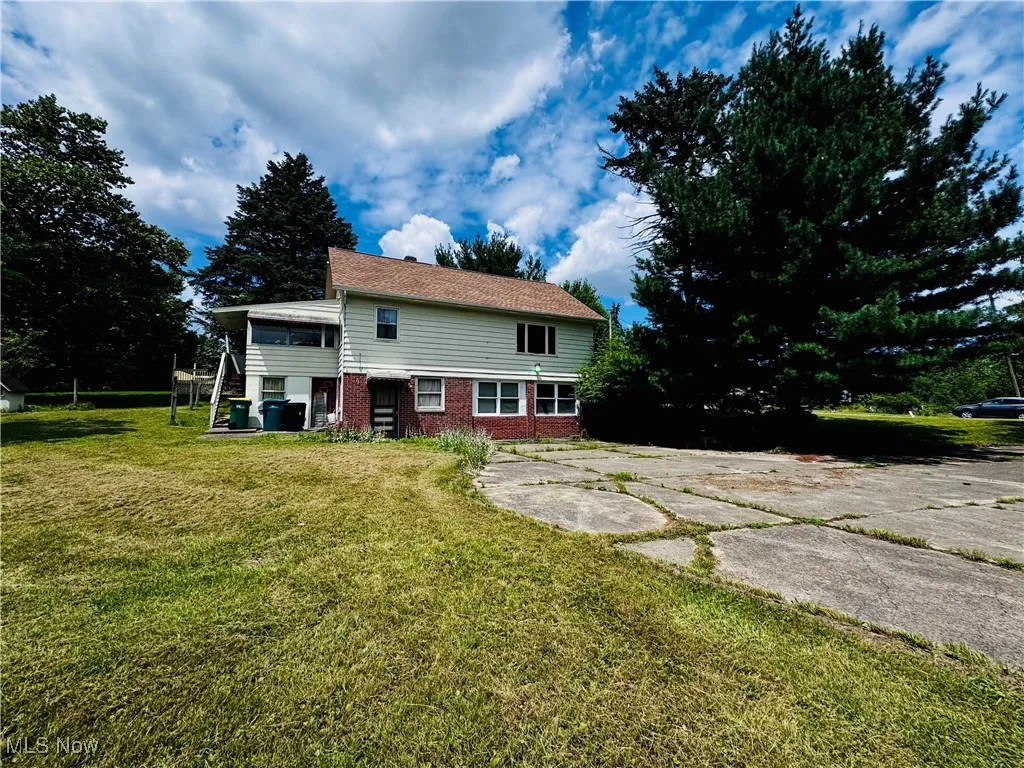 Back of property featuring brick siding and a lawn