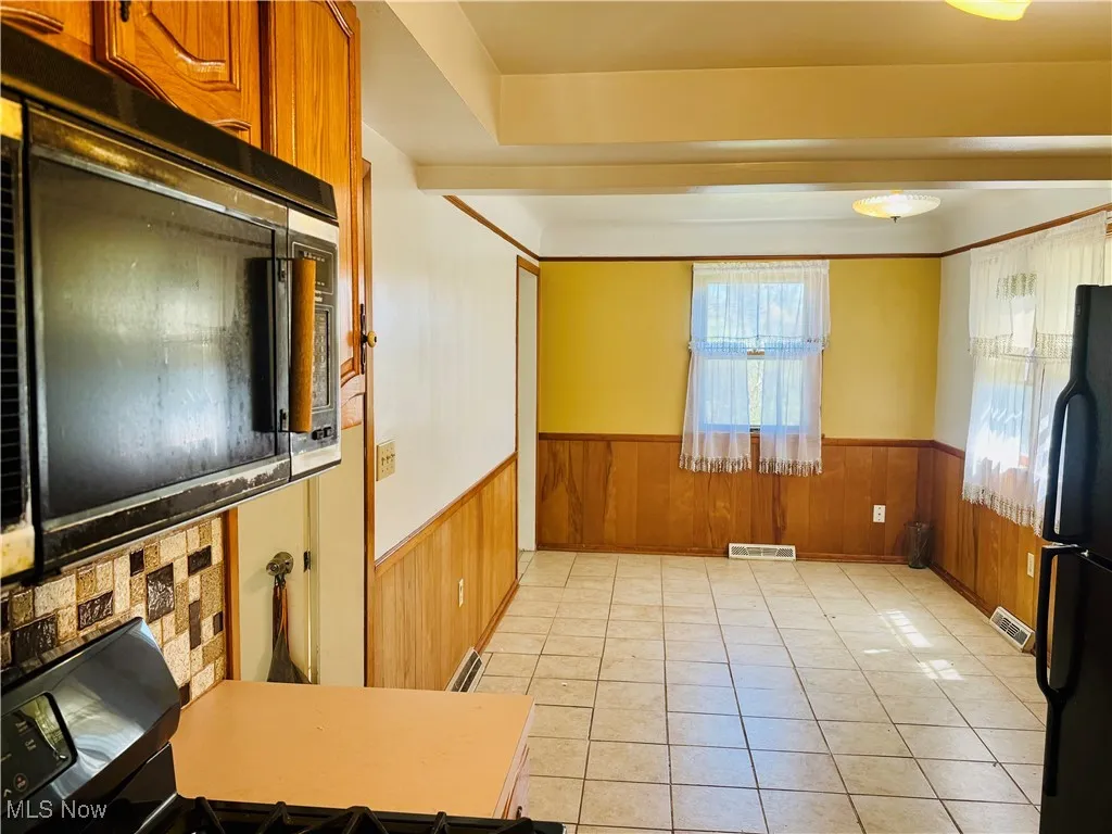From prep/Kitchen into dining area wainscoting, light tile patterned floors, and wooden walls