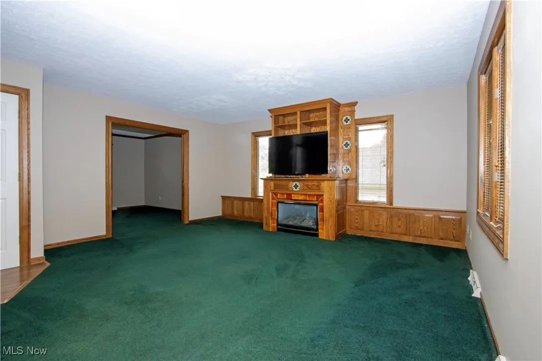 Unfurnished living room with carpet floors, a large fireplace, and a textured ceiling