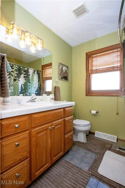 Full bathroom featuring visible vents, tile patterned flooring, toilet, and vanity