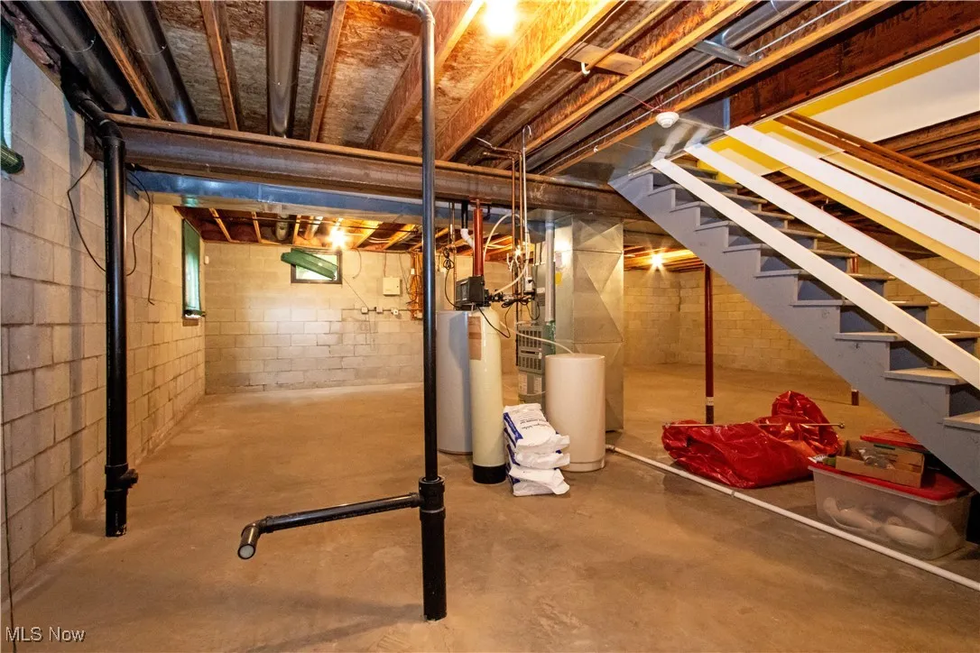 Unfinished below grade area with stairs and a water softener system