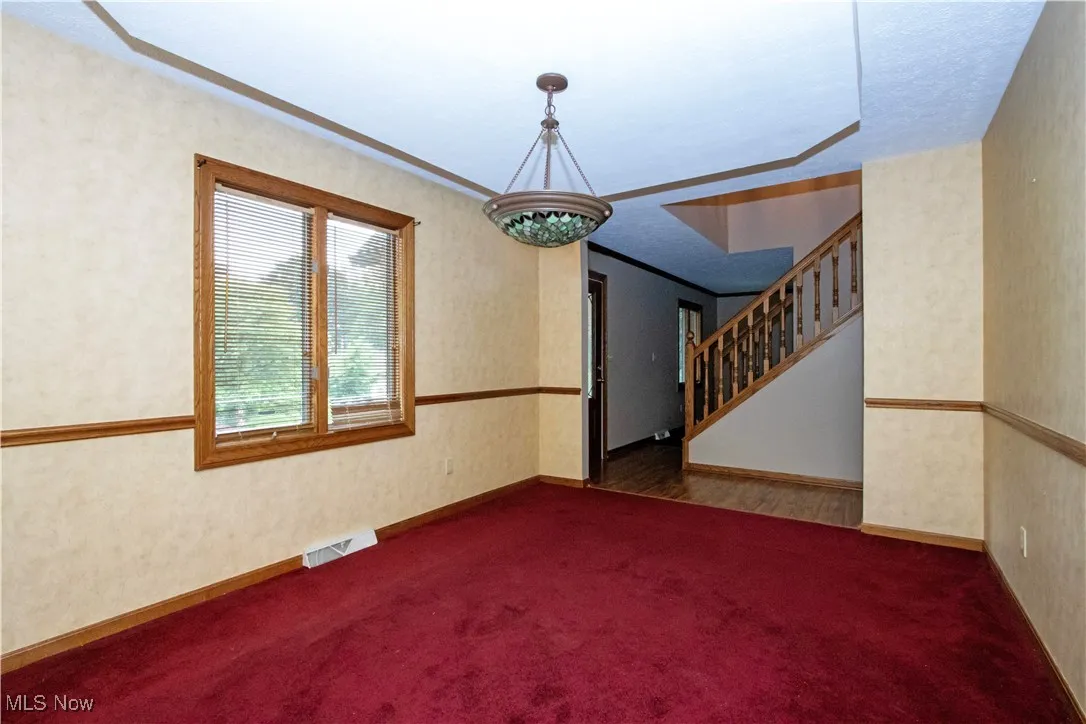 Carpeted spare room with stairs and ornamental molding