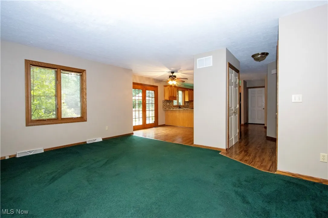 Unfurnished living room featuring carpet floors, a ceiling fan, and french doors