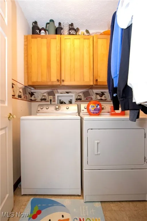 Washroom with a textured ceiling, cabinet space, and independent washer and dryer