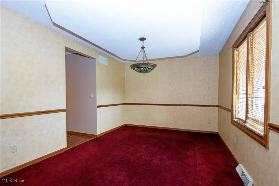 Spare room featuring carpet and wallpapered walls