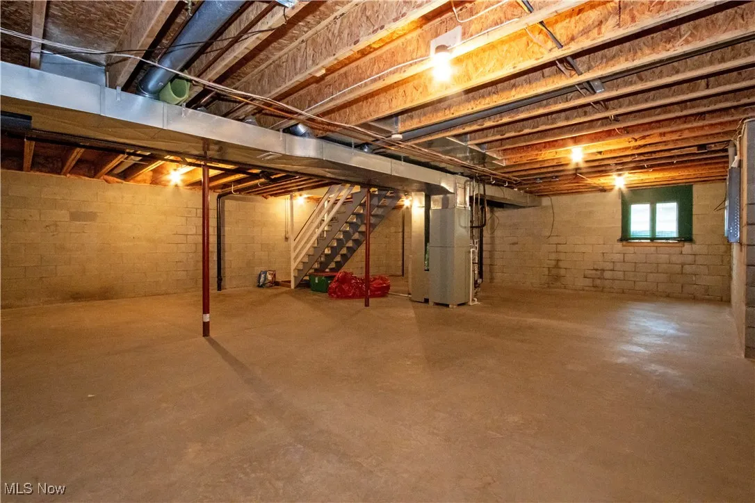 Basement featuring heating unit and stairs