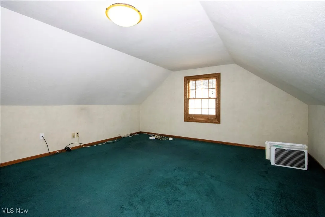 Bonus room with vaulted ceiling and carpet flooring