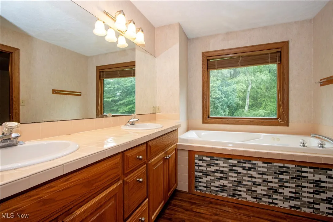 Full bath with plenty of natural light, double vanity, and a bath
