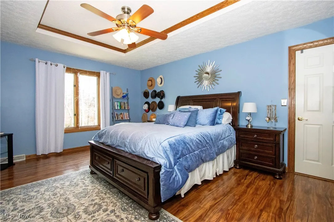 Bedroom with baseboards, a textured ceiling, ceiling fan, and wood finished floors