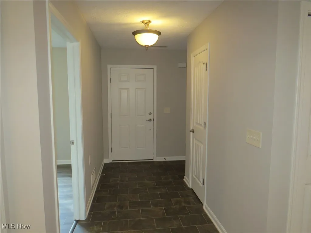 Hallway with baseboards and visible vents