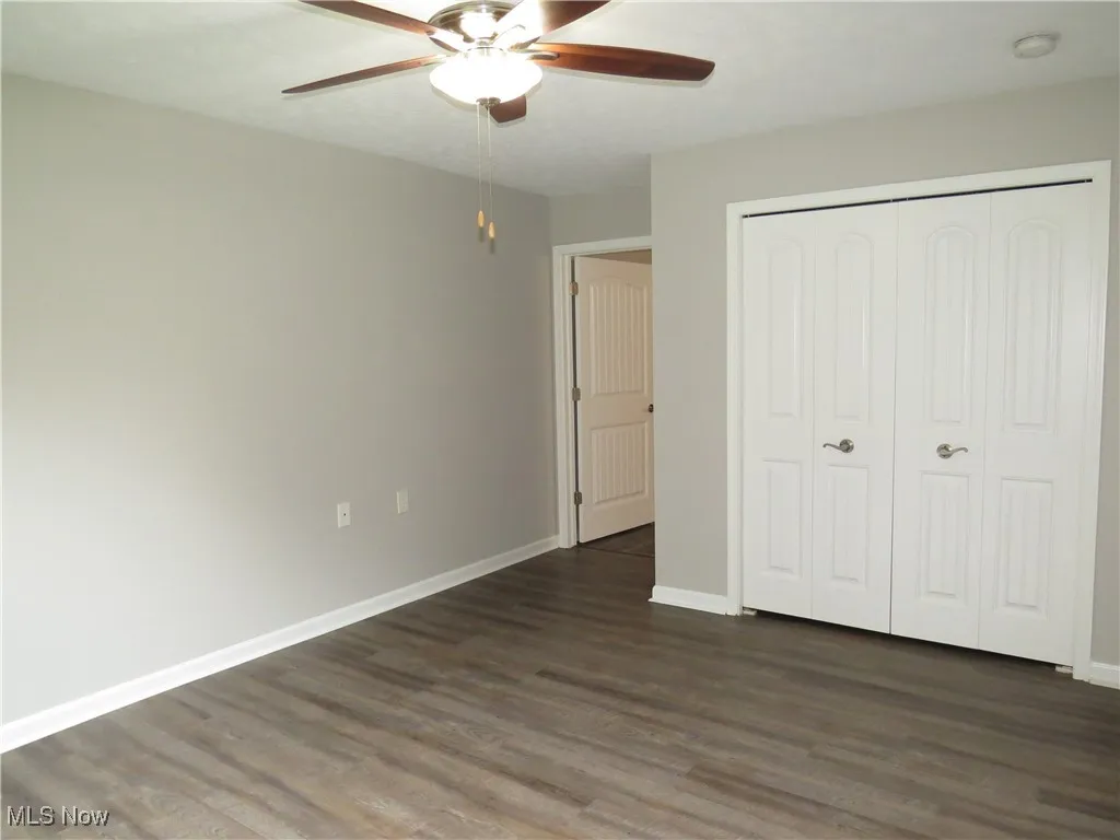 Unfurnished bedroom with baseboards, dark wood-style floors, and a closet