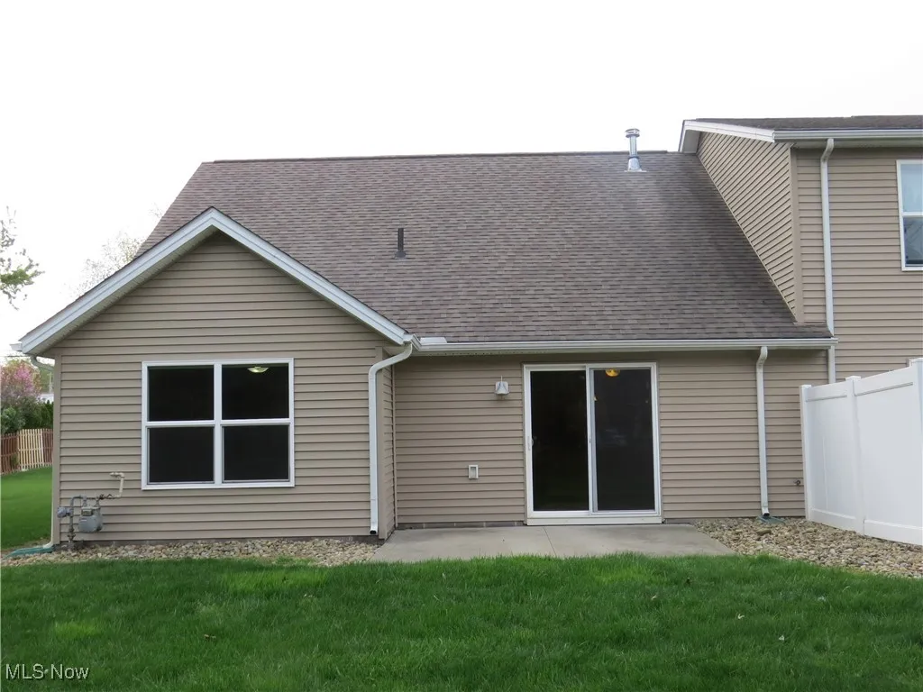 Rear view of property with a patio, a shingled roof, fence, and a yard