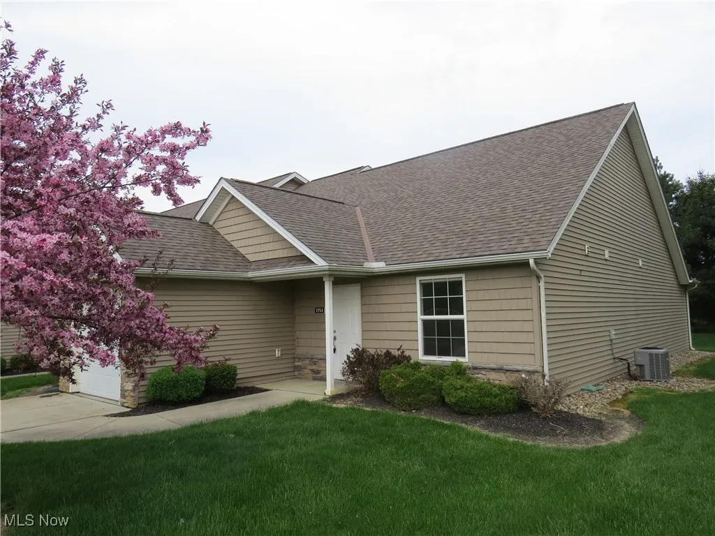 View of front facade with a shingled roof, central AC, and a front yard