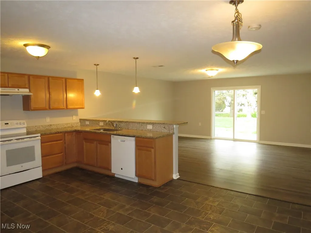 Kitchen featuring white appliances, a peninsula, open floor plan, baseboards, and under cabinet range hood