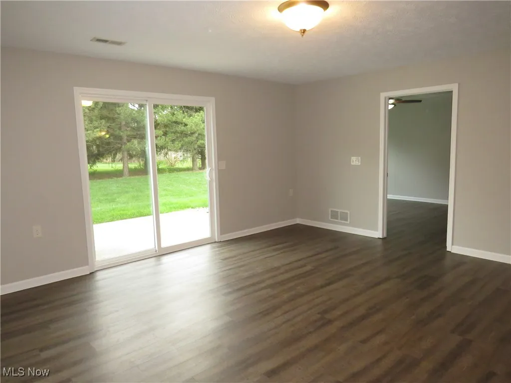 Living room featuring dark wood-style flooring, baseboards, and visible vents