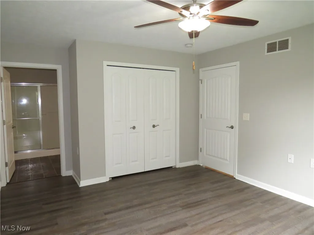 Unfurnished bedroom featuring visible vents, a closet, wood finished floors, baseboards, and a ceiling fan
