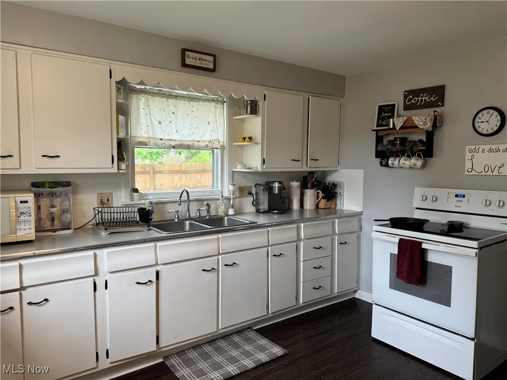 Kitchen featuring a sink, decorative backsplash, white cabinets, and white appliances