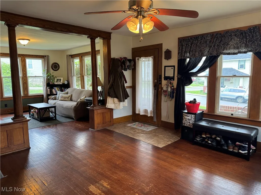 Foyer featuring a ceiling fan, baseboards, decorative columns, and wood finished floors
